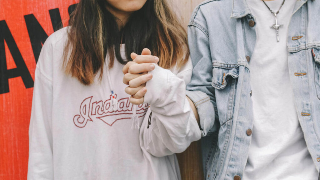 Two people holding hands intimately, showing the close bond that proves you are in love.